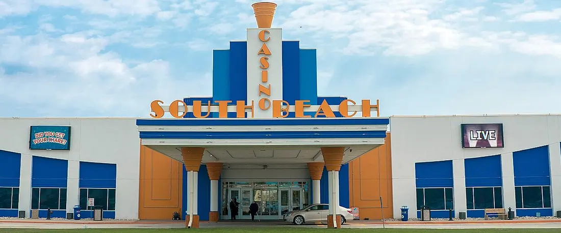 Front of South Beach Casino and Resort with its blue-and-orange facade and the hotel wing on the right